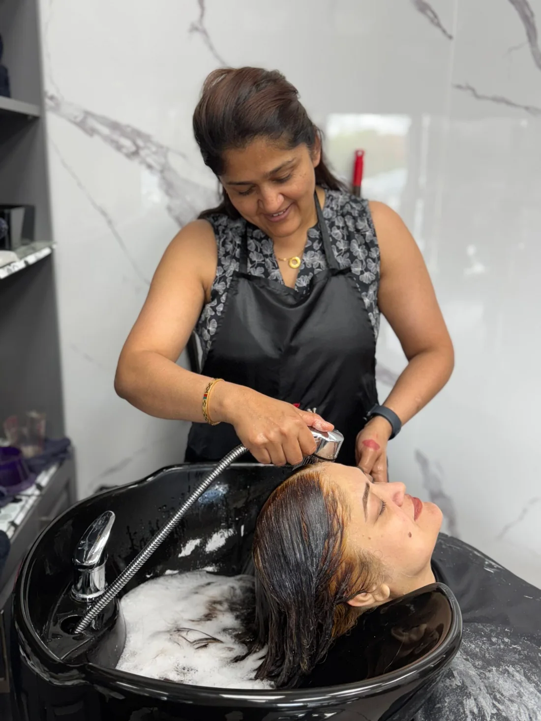A stylist washing a client’s hair at the salon basin